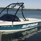 Boat with 'Supreme' decal on a dock by a lake
